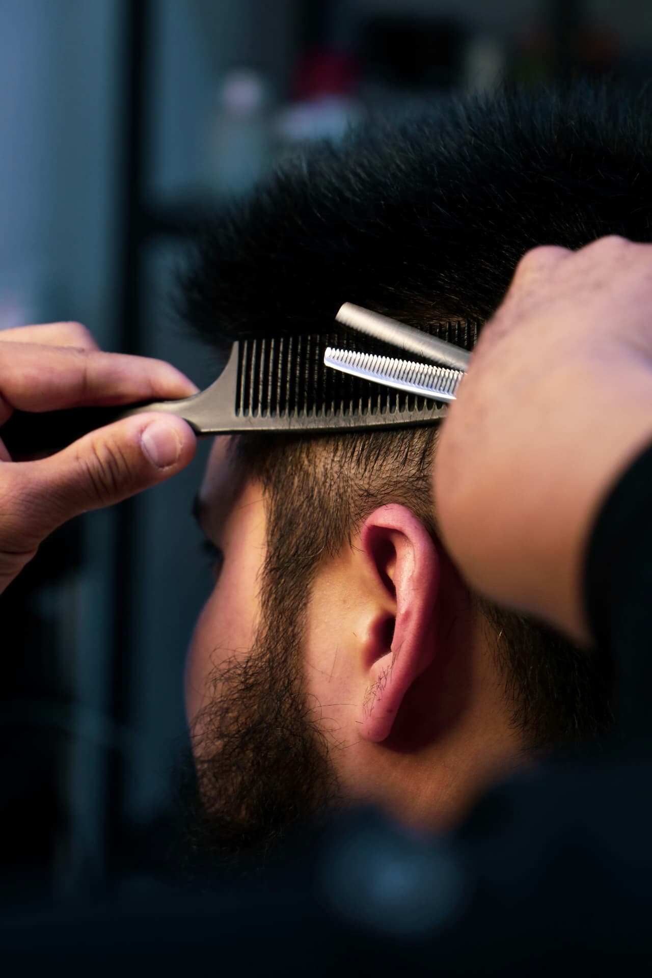 Barber texturising a client's hair with shears and comb